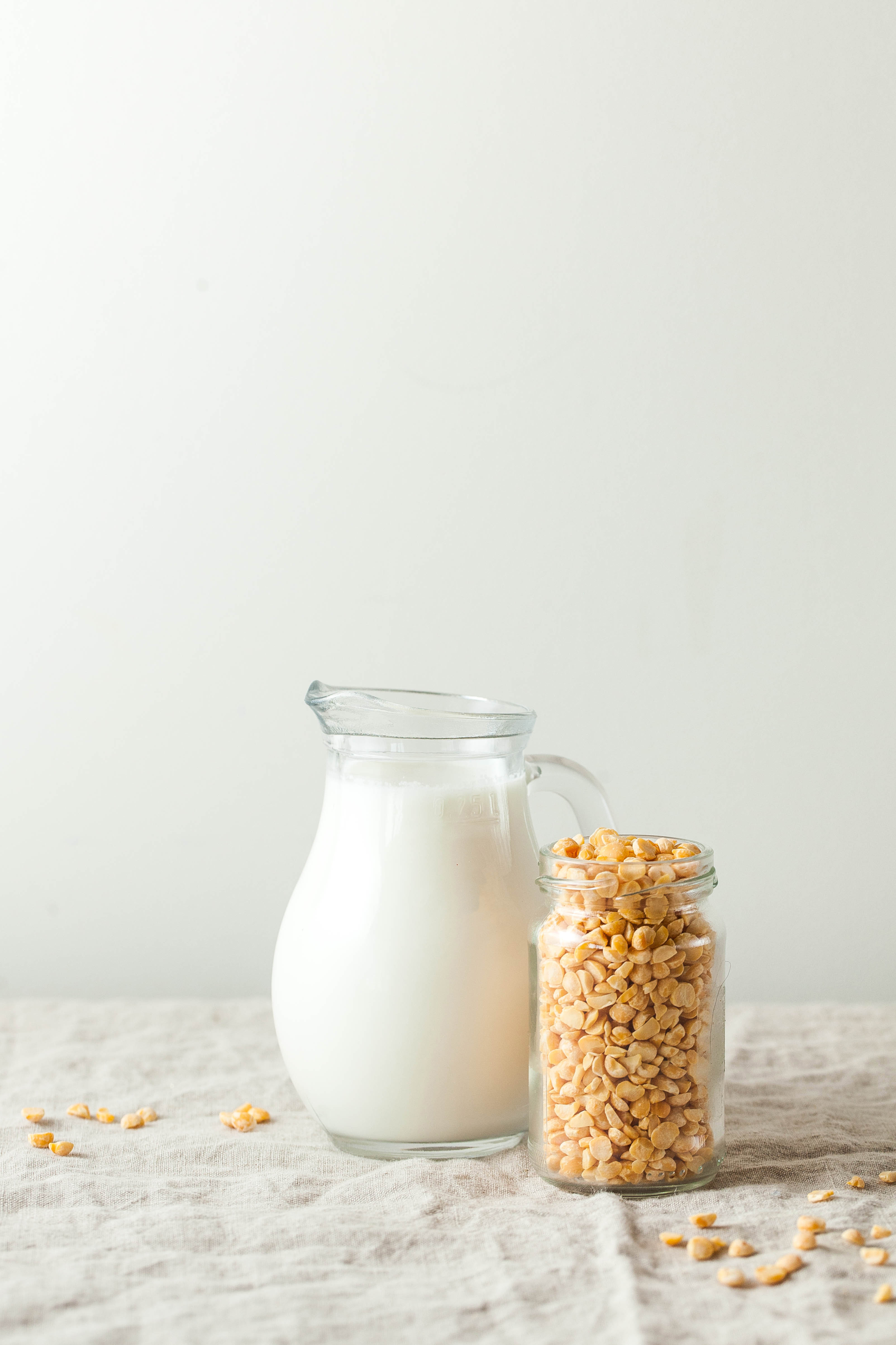 Pitcher of nondairy beverage made from pea protein next to a jar of dried peas.